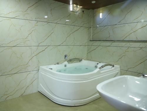 a bathroom with a bath tub and a sink at Cosmos Resort Maliblu in Indore