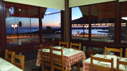 a restaurant with tables and chairs and a view of the ocean at Pousada Farol do Portinho in Vila Praia de Âncora