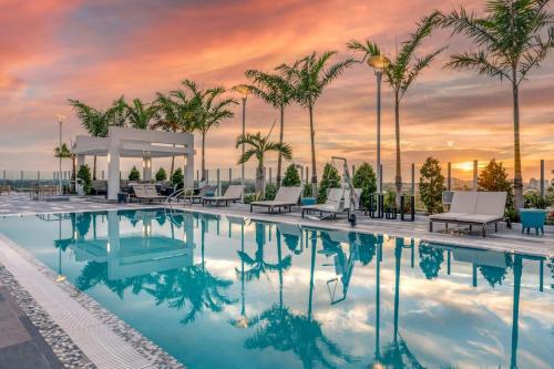 a pool with chairs and palm trees at sunset at Courtyard by Marriott Fort Lauderdale Downtown in Fort Lauderdale