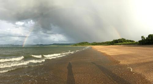 a beach with a rainbow in the sky and the ocean at Kite Bungalow Bahia Salinas in La Cruz