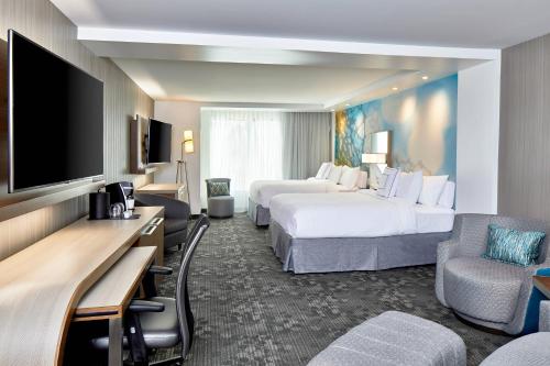 a hotel room with two beds and a flat screen tv at Courtyard Baltimore Downtown/McHenry Row in Baltimore