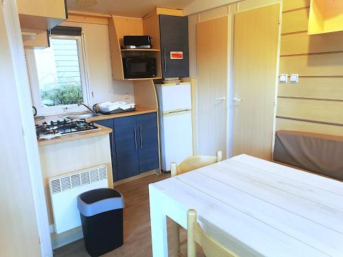 une petite cuisine avec une table blanche et une cuisinière dans l'établissement Bungalow tout confort 2ch 5pers 400DJ, à La Boissière-de-Montaigu