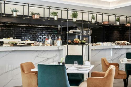 a restaurant with a table and chairs and a kitchen at Academias Hotel, Autograph Collection in Athens