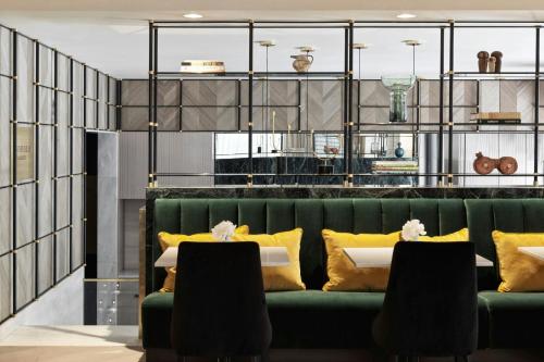 a green couch with yellow pillows and a table at Academias Hotel, Autograph Collection in Athens