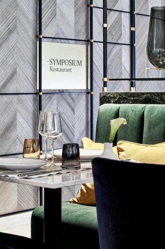 a dining room with a glass table and green chairs at Academias Hotel, Autograph Collection in Athens