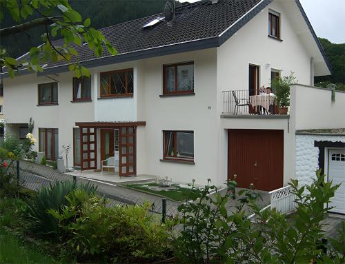 a white house with a table on a balcony at Regina's Gästehaus in Weisenbach