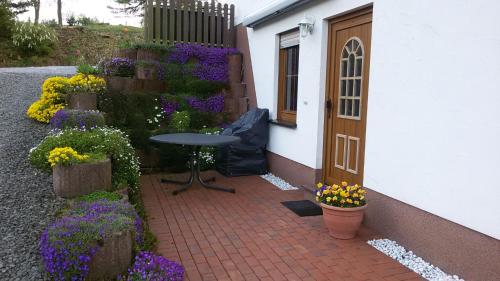 a patio with flowers and a table next to a door at Ferienwohnung, 55qm in Herscheid