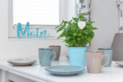 エセンスにあるRobbeのカップや皿、鉢植えの植物が置かれたテーブル