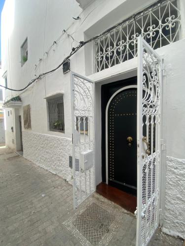 a white building with a gate and a black door at Dar La Casbah Private Riad Stay with Moroccan Breakfast in Tangier