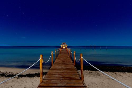 a wooden pier leading into the ocean at night at LOB LOB Cabañas in Dzilam de Bravo