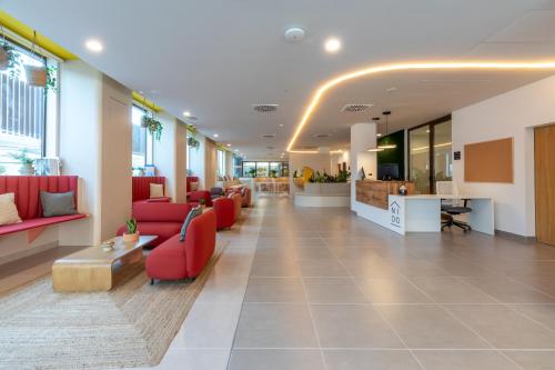 a lobby of a hospital with red chairs and tables at NIDO Malvarrosa Hotel - Apartamento in Valencia