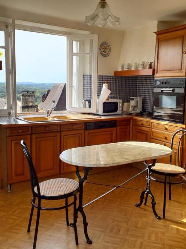 une cuisine avec une table et deux chaises ainsi qu'une fenêtre dans l'établissement Gîte de Louis - Vue imprenable - centre de Domme, à Domme
