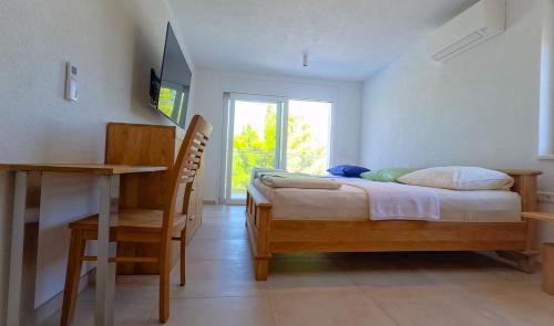 a bedroom with a bed and a desk and a window at Villa Anto in Pridraga