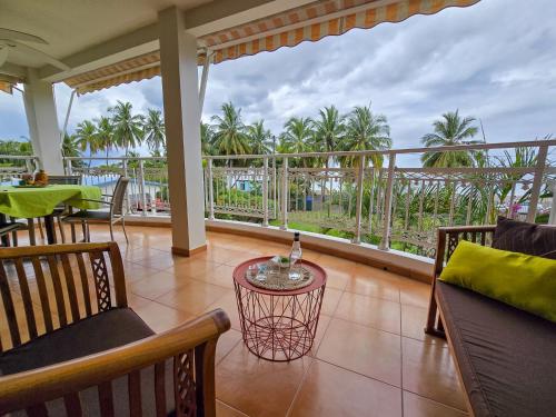 a balcony with a table and chairs and palm trees at Kay Carbet - Accès plage direct in Le Carbet