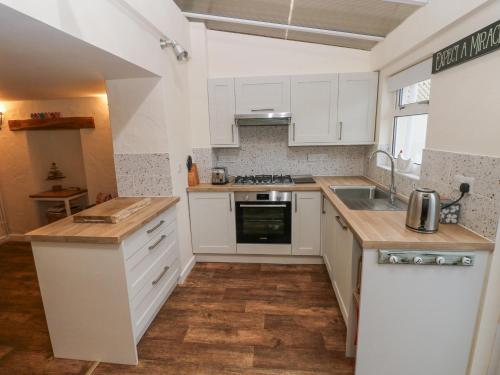 a kitchen with white cabinets and a counter top at Bank House in Newcastle Emlyn