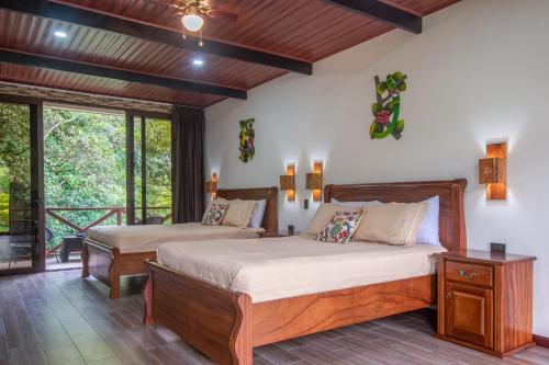 a bedroom with two beds and a balcony at Cabañas Refugio Verde Monteverde in Monteverde Costa Rica