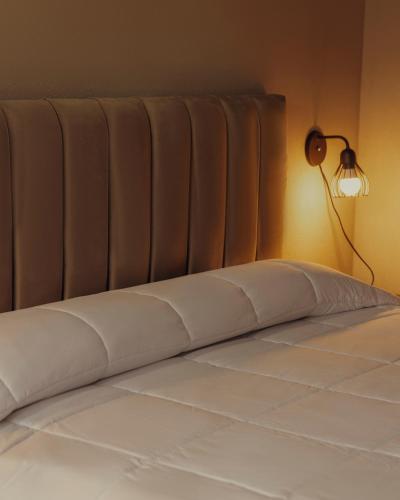 a bed with a white mattress and a light on the wall at Olivos de Monte in San Miguel del Monte