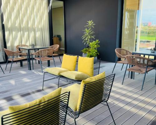 a patio with chairs and tables with yellow pillows at Lusitano Garden Villas in Ponta Delgada