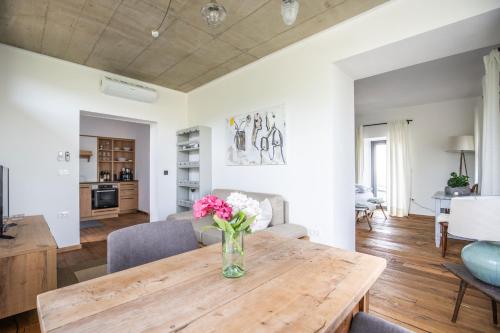 a dining room and living room with a wooden table and flowers at Winzarei Ciringa Stampfer in Svečina