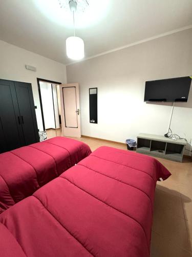 a living room with two red beds and a flat screen tv at La Casa Di Gioia in Pagani