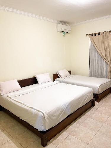 two beds sitting next to each other in a room at d'Alvin Double Room in Labuan Bajo
