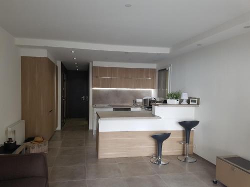 - une cuisine avec un comptoir et quelques tabourets dans l'établissement Appartement les pieds dans l'eau avec terrasse et jardin, à Bandol