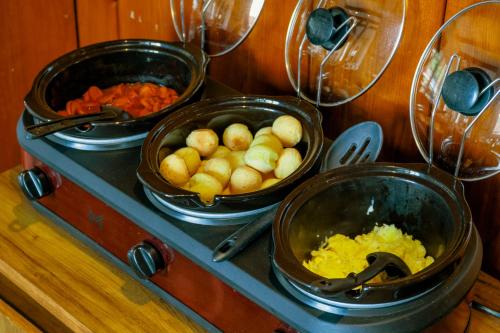 a stove with three pans of food on it at VELINN Pousada Casa de Campos Capivari House in Campos do Jordão