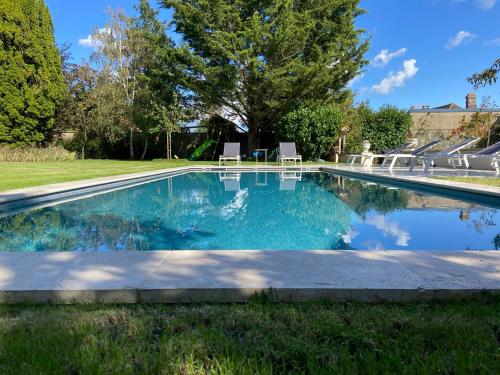 - une piscine dans une cour avec des chaises dans l'herbe dans l'établissement Bel Air, à Bois-le-Roi