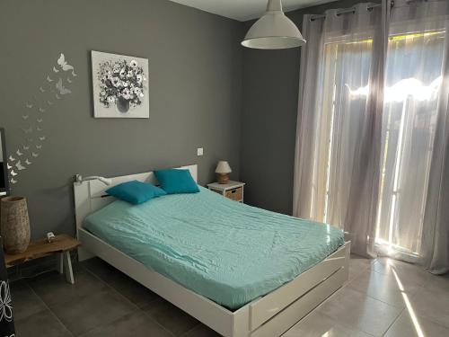 a bedroom with a bed with blue pillows and a window at Villa en pleine nature avec piscine in Sablières