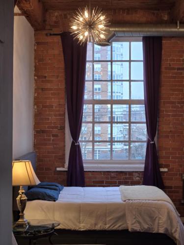 a bedroom with a brick wall and a large window at Detroit Artsy Industrial Loft in Detroit