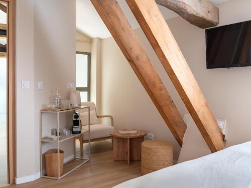 a room with a bed and a chair and a tv at Le Pavillon des Capitans in Juliénas