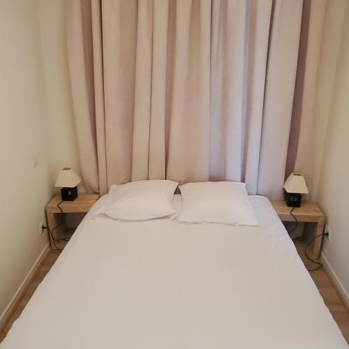 - un lit blanc dans une chambre avec deux lampes dans l'établissement L'Horizon - Parking - Piscine, à La Rochelle