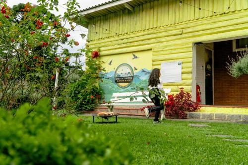 a woman walking past a building with a mural on it at VELINN Pousada Casa de Campos Capivari House in Campos do Jordão