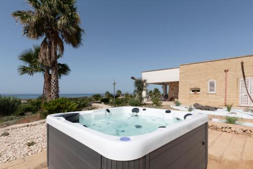 a hot tub on a patio with a palm tree at Le Gioie - Villa Macchia Mediterranea - Splendida villa vista mare immersa nel verde in Torre Pali 