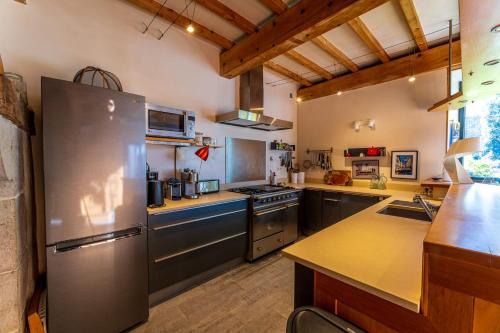 Una cocina grande con refrigerador de acero inoxidable. en Grand gîte 4 étoiles - Bain nordique, en Aste-Béon