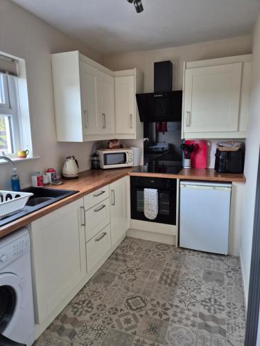 a kitchen with white cabinets and a stove top oven at RAWSON COTTAGE LOVELY 2 BEDROOM SEMI RURAL in Stranraer