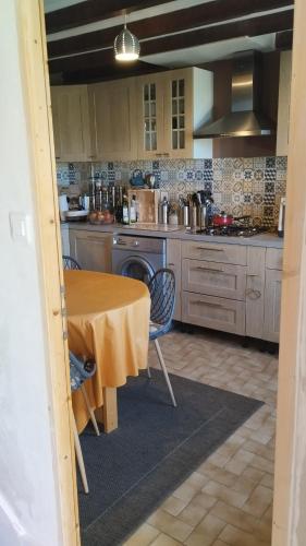 une cuisine avec une table et une cuisine avec une cuisinière dans l'établissement Maison de vacances belle campagne auvergnate en Combrailles, à Saint-Julien-la-Geneste
