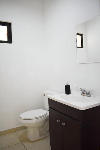 a white bathroom with a toilet and a sink at ALBERCA 3 HABITACIONES, CERCA DE LA PLAYA, Cantera Residencial in San Carlos