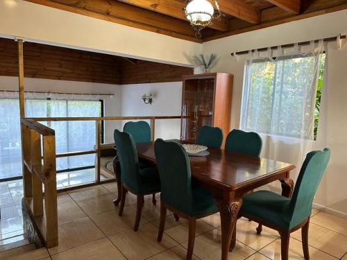 a dining room with a wooden table and green chairs at Casa Takarua in Hanga Roa