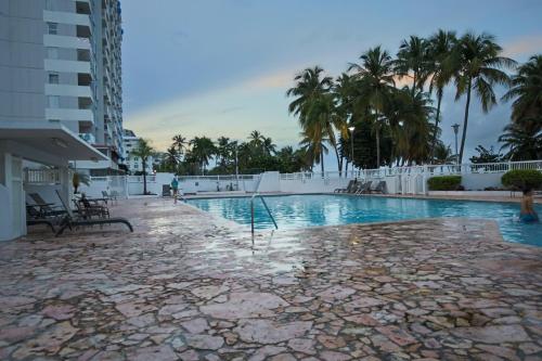 a swimming pool at a resort with palm trees at Mi estadía in San Juan