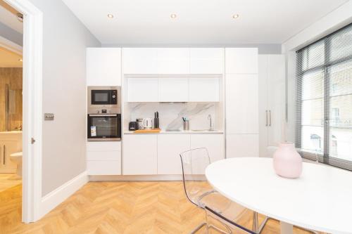 a white kitchen with a white table and chairs at Luxury Apartments In Paddington in London