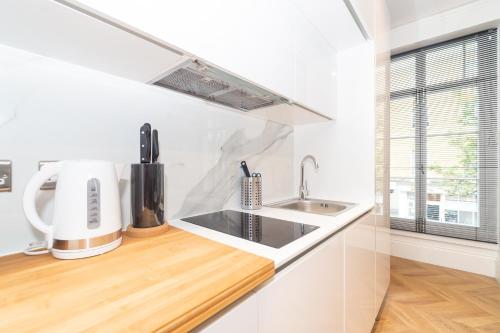 a white kitchen with a sink and a window at Luxury Apartments In Paddington in London