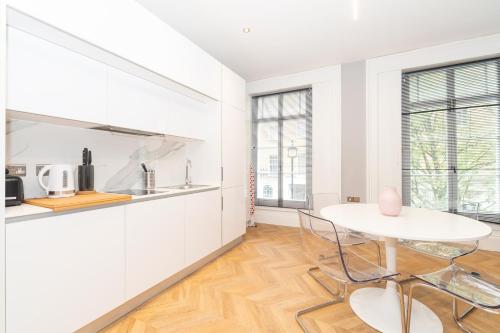 a white kitchen with a table and chairs at Luxury Apartments In Paddington in London