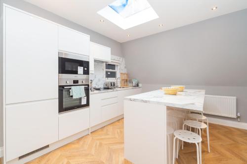 a kitchen with white cabinets and a skylight at Luxury Apartments In Paddington in London