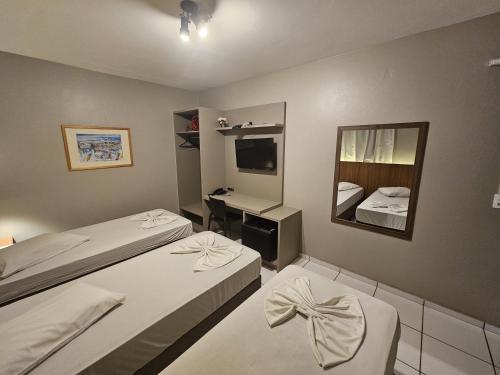 a bedroom with two beds and a sink and a mirror at Ok Inn Hotel Criciúma Centro in Criciúma
