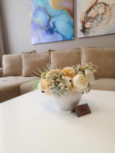 a white vase with flowers on a table with a couch at Mianelly Center in Constanţa