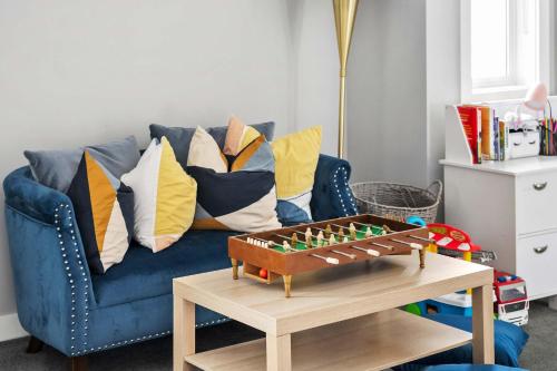 ein blaues Sofa mit Kissen und einem Tisch in der Unterkunft Large Family 4BR w Kid's Play Den! Near Airport & Shopping! FREE Banff Pass, BBQ, Netflix, Parking & Wine! in Calgary