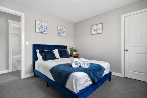 sypialnia z niebiesko-białym łóżkiem z ręcznikami w obiekcie NEW! Large Family 4BR w Kid's Play Den, Yard - FREE Banff Pass, BBQ, Netflix, Parking & Wine! w mieście Calgary