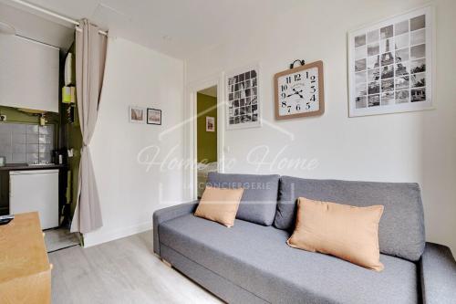 un salon avec un canapé et une horloge au mur dans l'établissement Cozy & Relaxing Stay with Green Bedroom in Pantin, à Pantin