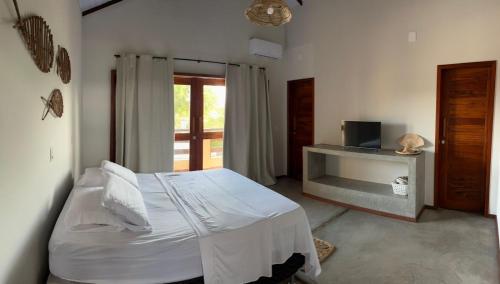 a bedroom with a bed and a desk with a television at Casa Vivienda - Barra Grande in Barra Grande
